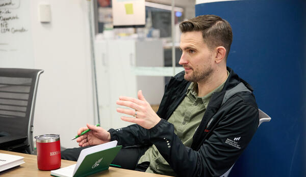 David Brown sits at a desk, talking to someone off camera.