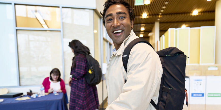Nikhil smiling walking down the MIT Sloan hallway, wearing a backpack