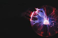 Plasma Globe with a black background and a hand over it