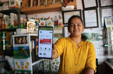 A retail shop owner demonstrates the Essmart mobile app on her smartphone.