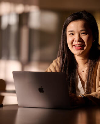 MBA Student Sharon Fan sits behind a laptop
