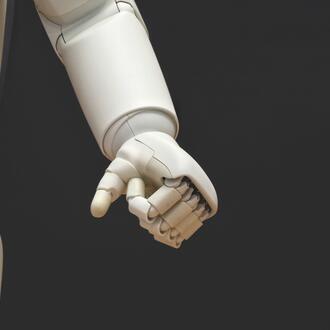 Image of white robotic hand on black background.