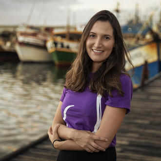 Portrait of Barbara Granek, alumni and CEO and founder of Fishtag on dock in front of fishing boats