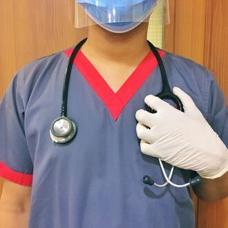 Nurse in face shield and mask with stethoscope draped over her shoulders