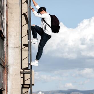 Image of a Man With Backpack Climbing a Ladder