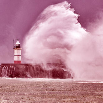 Huge waves crash over harbor sea wall and lighthouse