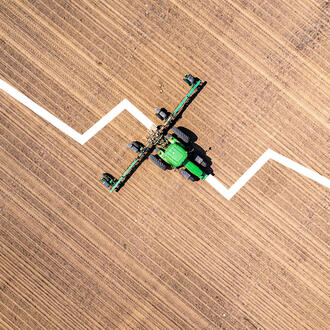 A downward sloped graph is overlayed on top of a John Deere tractor photograph
