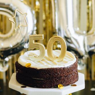 A chocolate cake on a stand with the number 50 on top of it