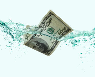 A hundred dollar bill floats in water