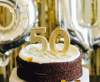 A chocolate cake on a stand with the number 50 on top of it