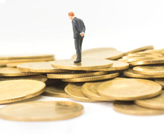 A business person thinking while walking on a pile of gold coins
