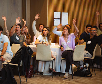 MIT MBA students raising their hands at an orientation program