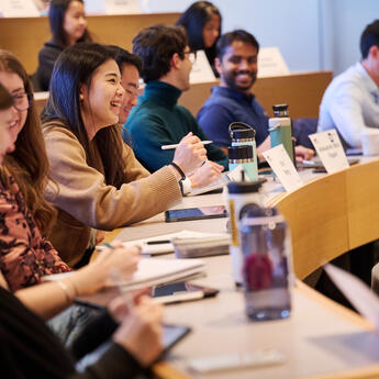 A group of smiling students engage with each other in a classroom setting