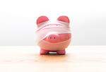 image of a pink piggy bank wrapped in white gauze bandages