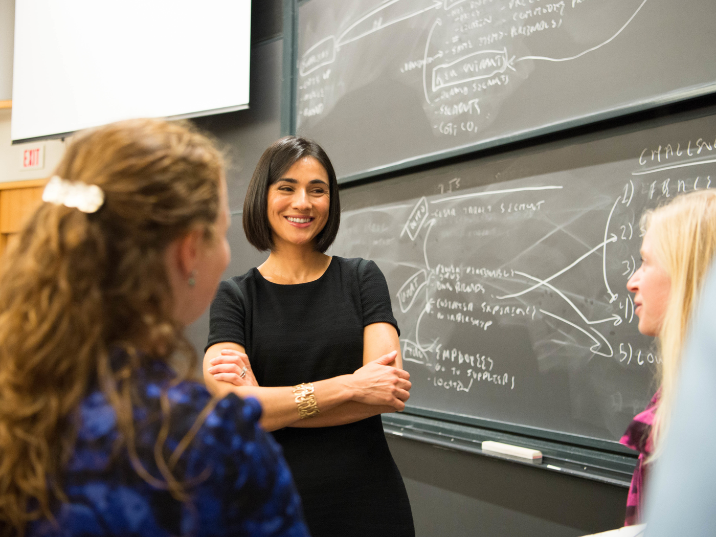 professor at chalkboard talking with students