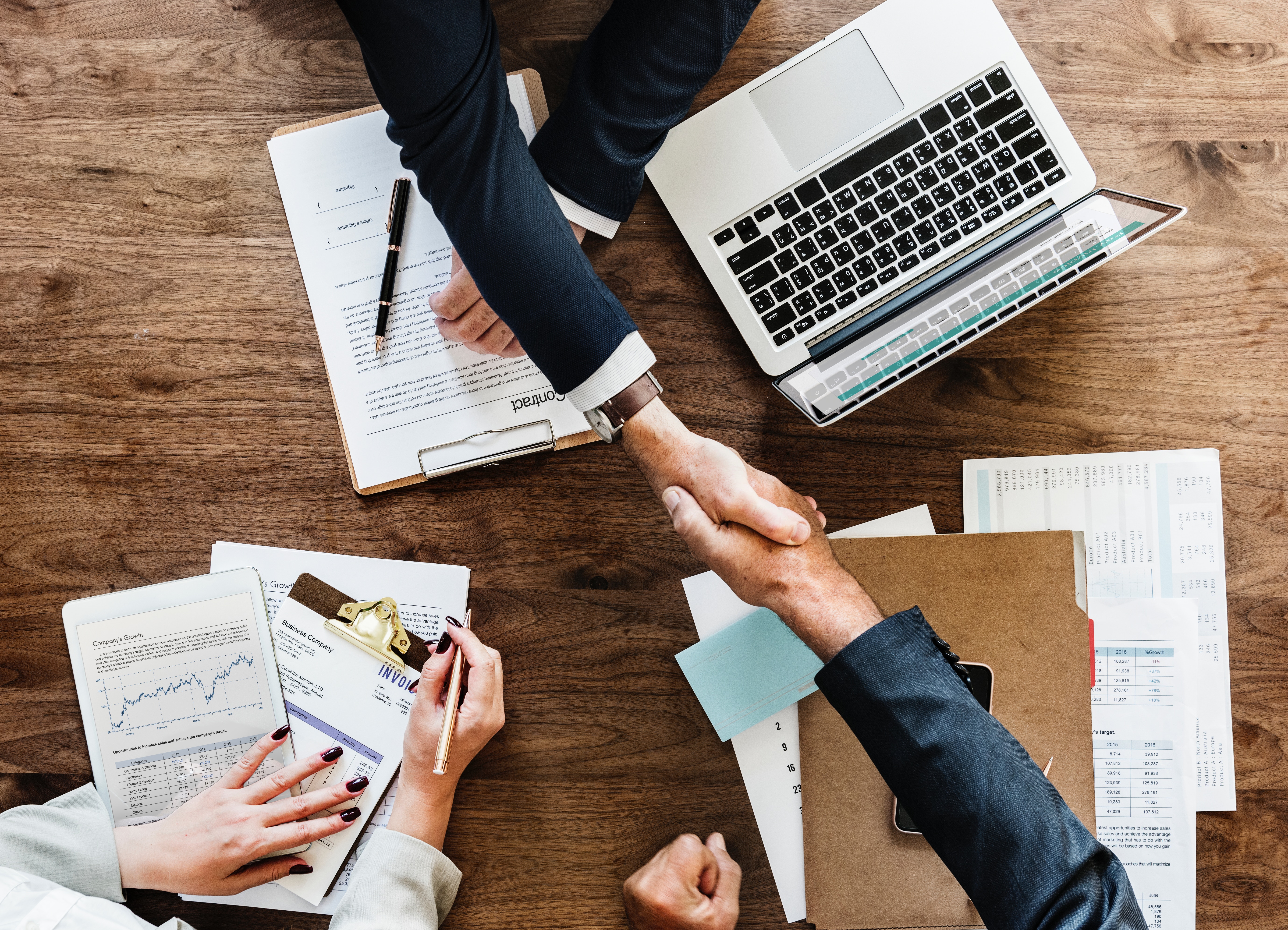 Men shaking hands over desk