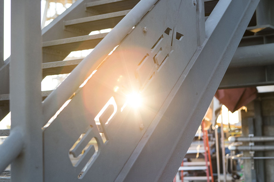 A railing with the sun shining through the SpaceX logo