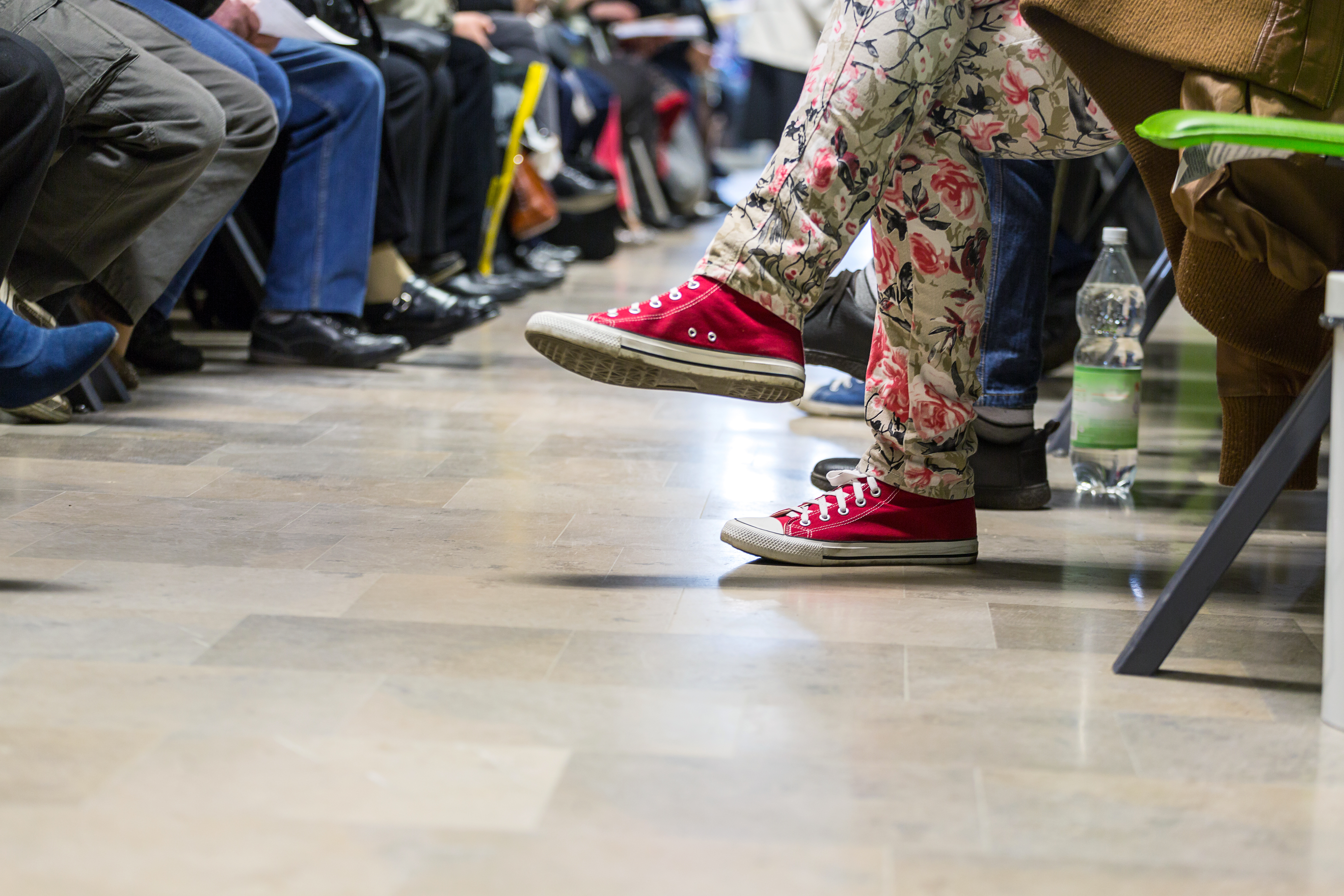 row of people sitting with only legs visible