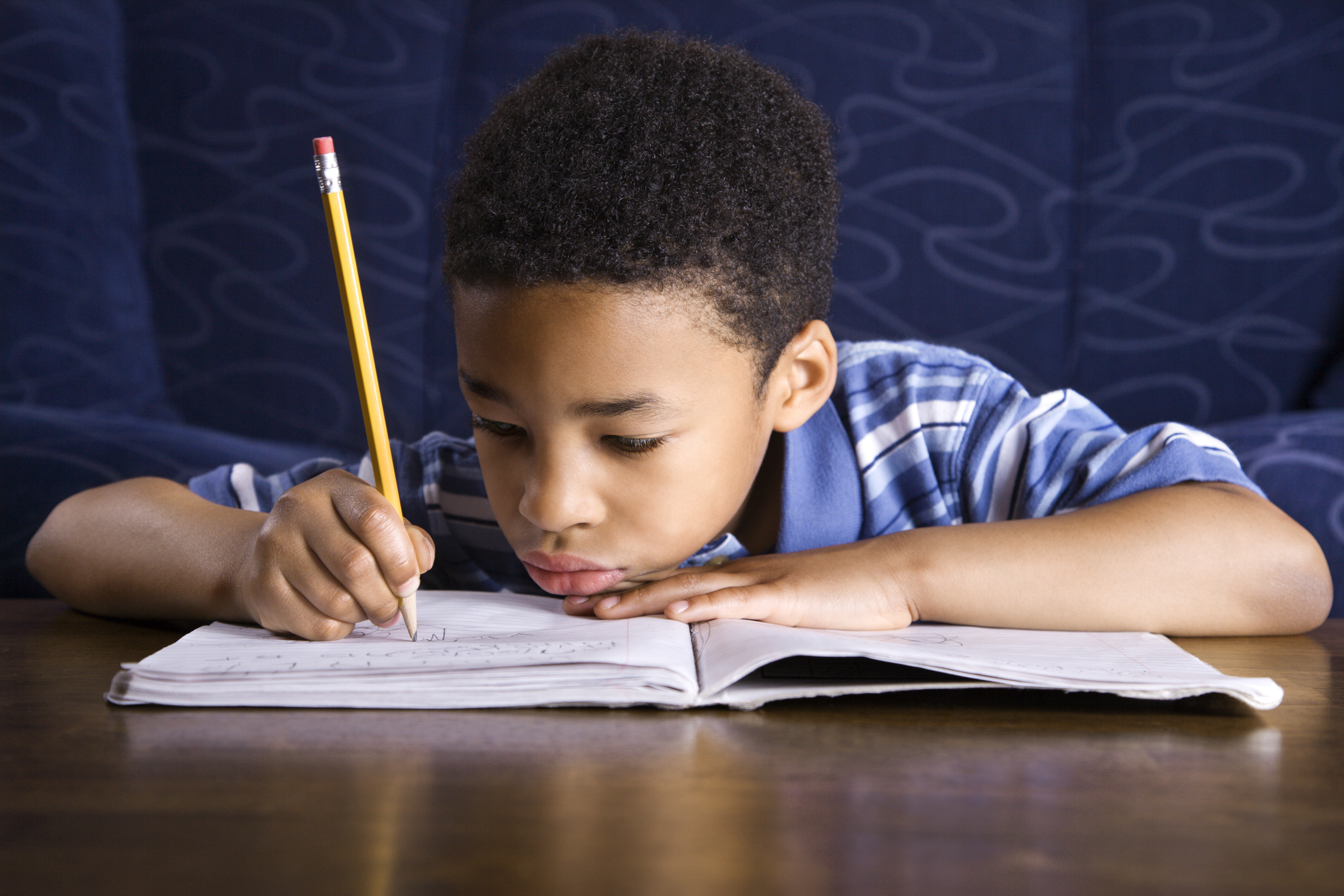 Child writing in book with a pencil
