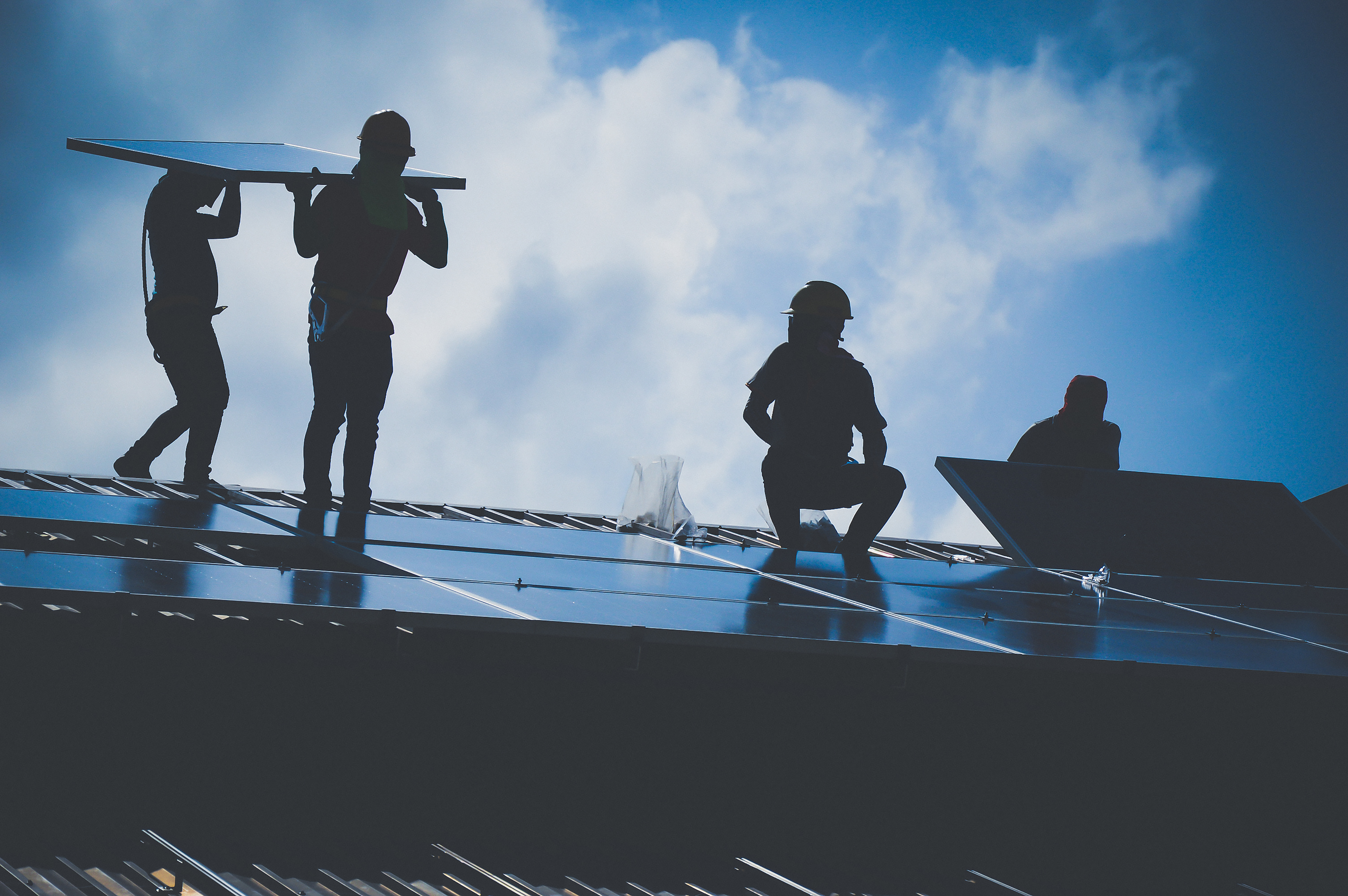 four people installing solar panels