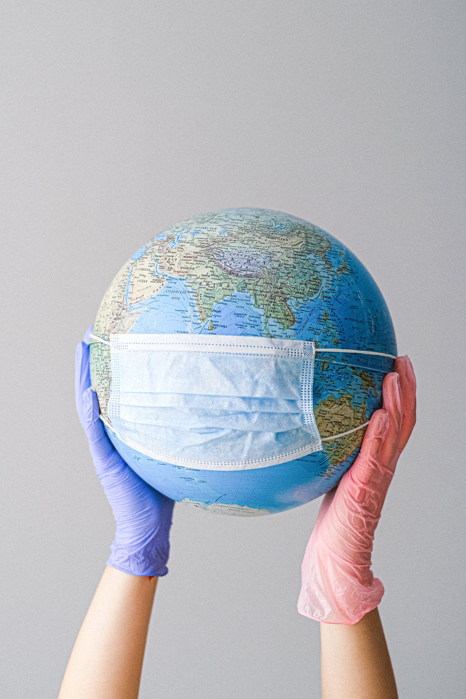 Hands with latex gloves holding a globe with a face mask