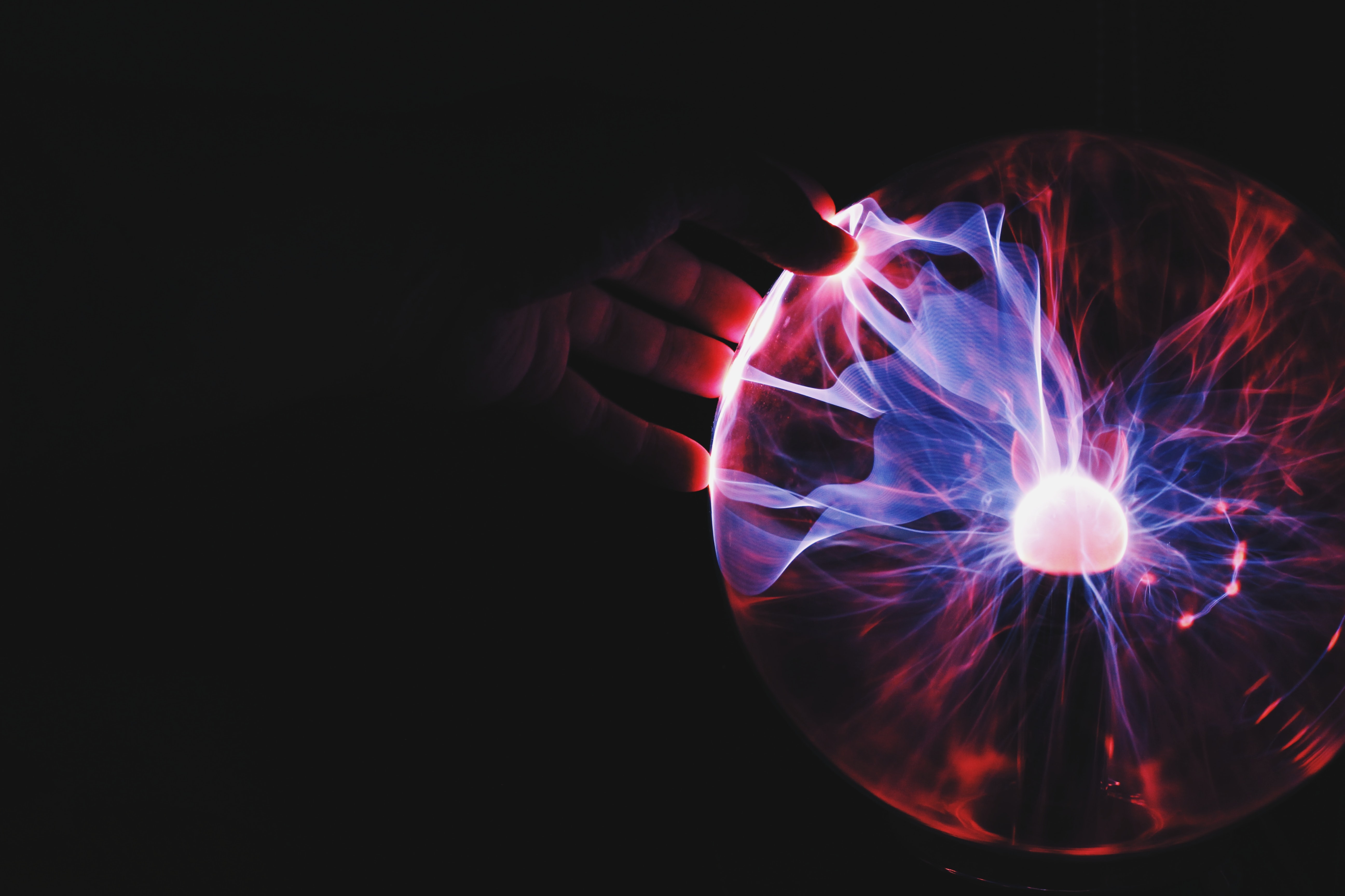 Plasma Globe with a black background and a hand over it