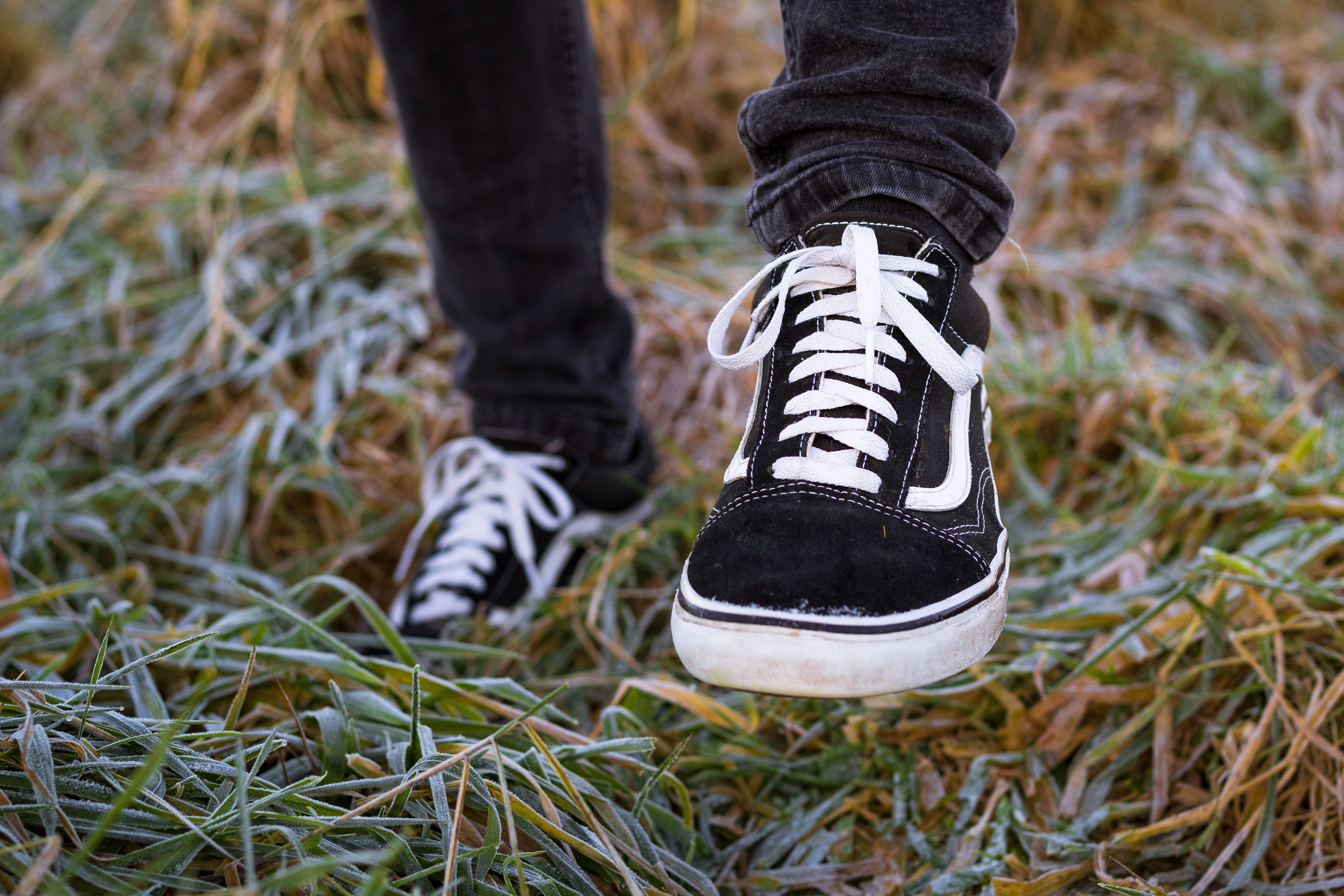 Close up of black sneakers on feet, standing on grass