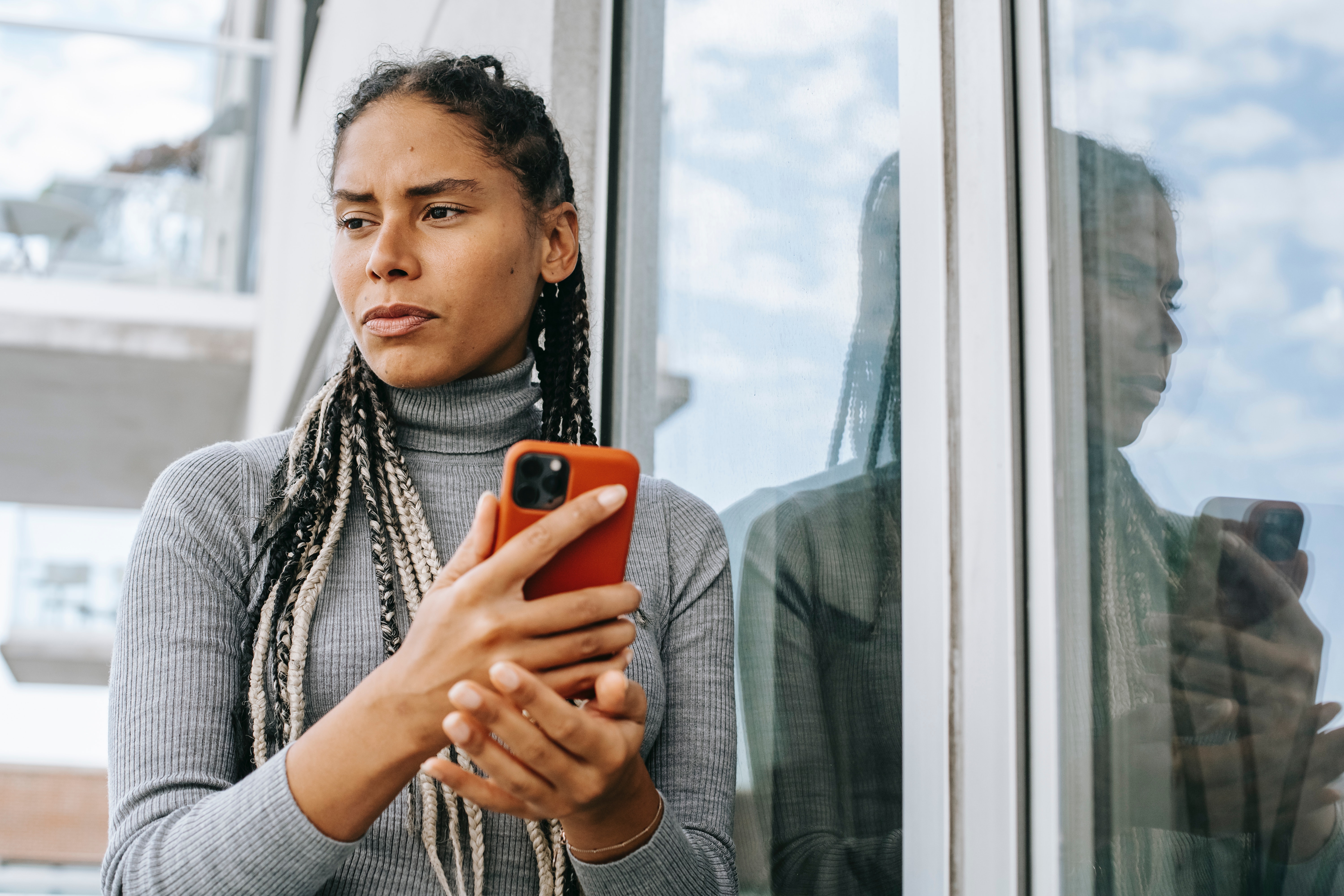Image of a woman holding a cellphone and thinking things over