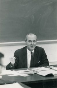 Black and white image of Charles Myers behind a desk