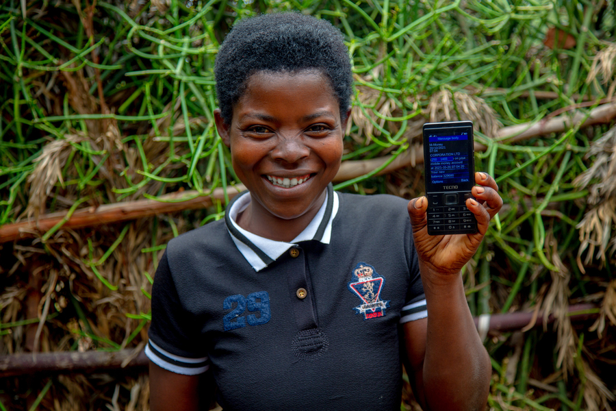 A child holds a phone displaying the GiveDirectly cash payment system.
