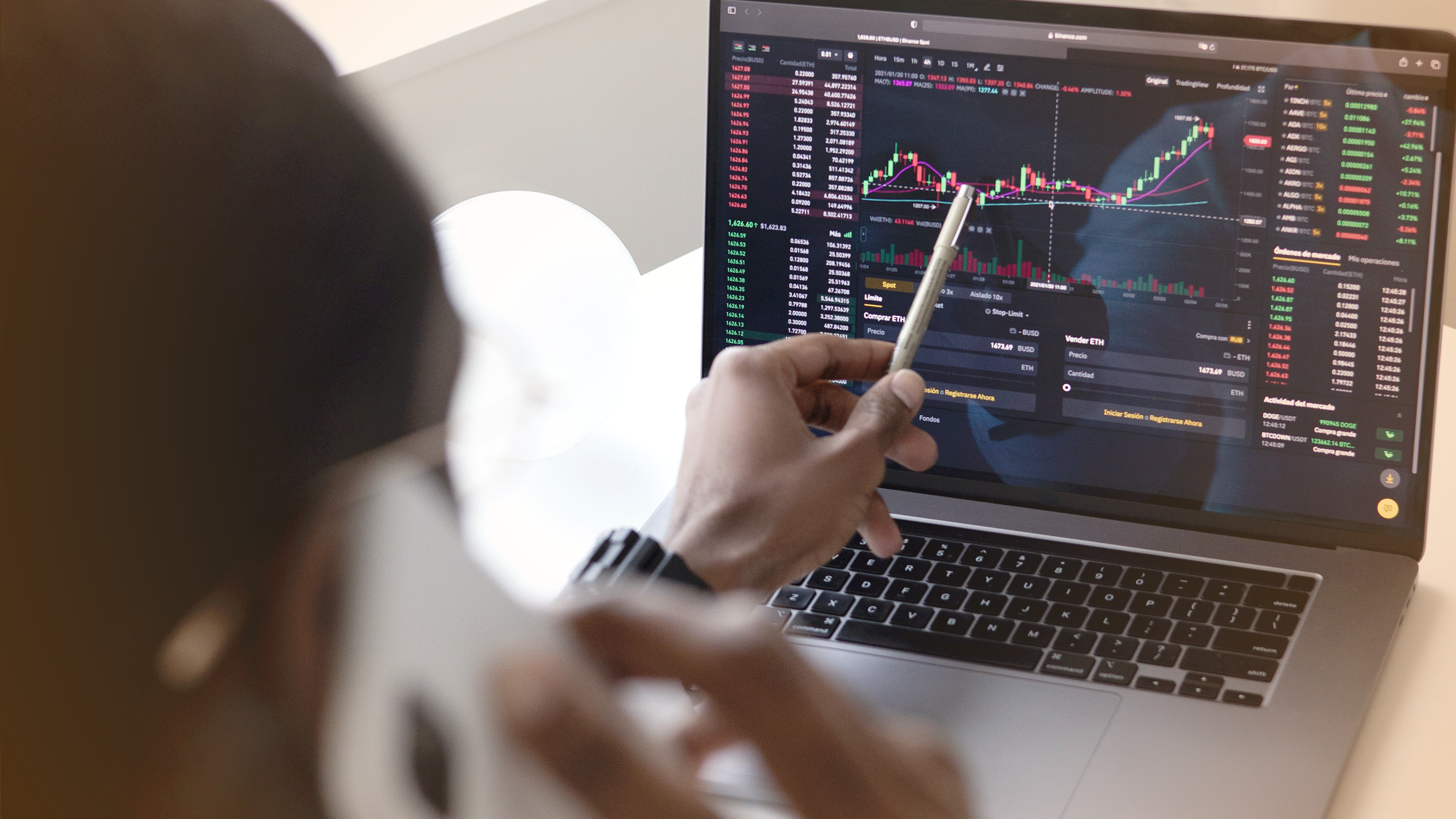Person using pen to point at stock trends on a laptop