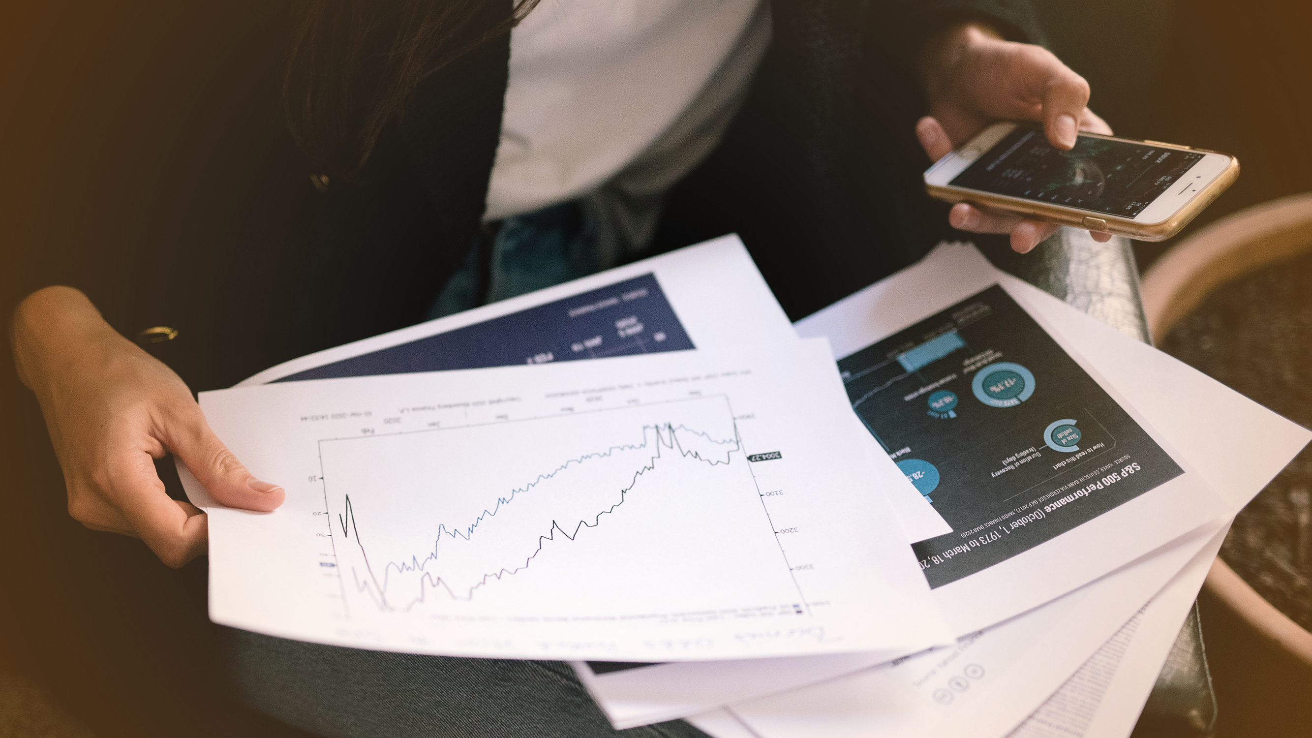 Person looking at papers showing stock trends