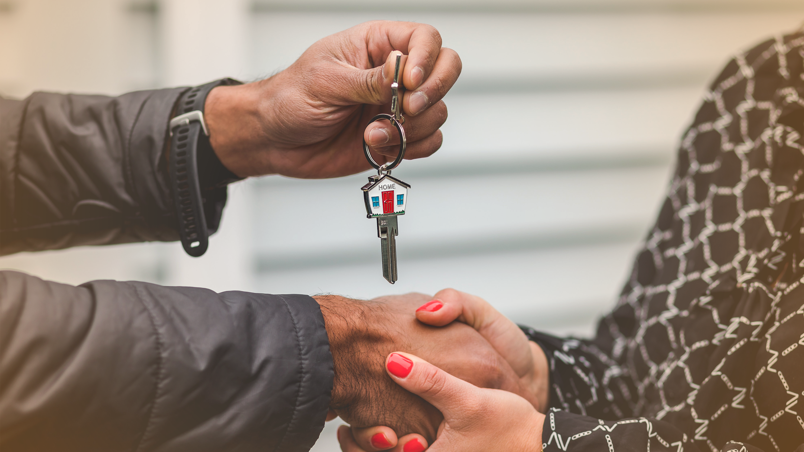Two people shaking hands and exchanging a set of house keys
