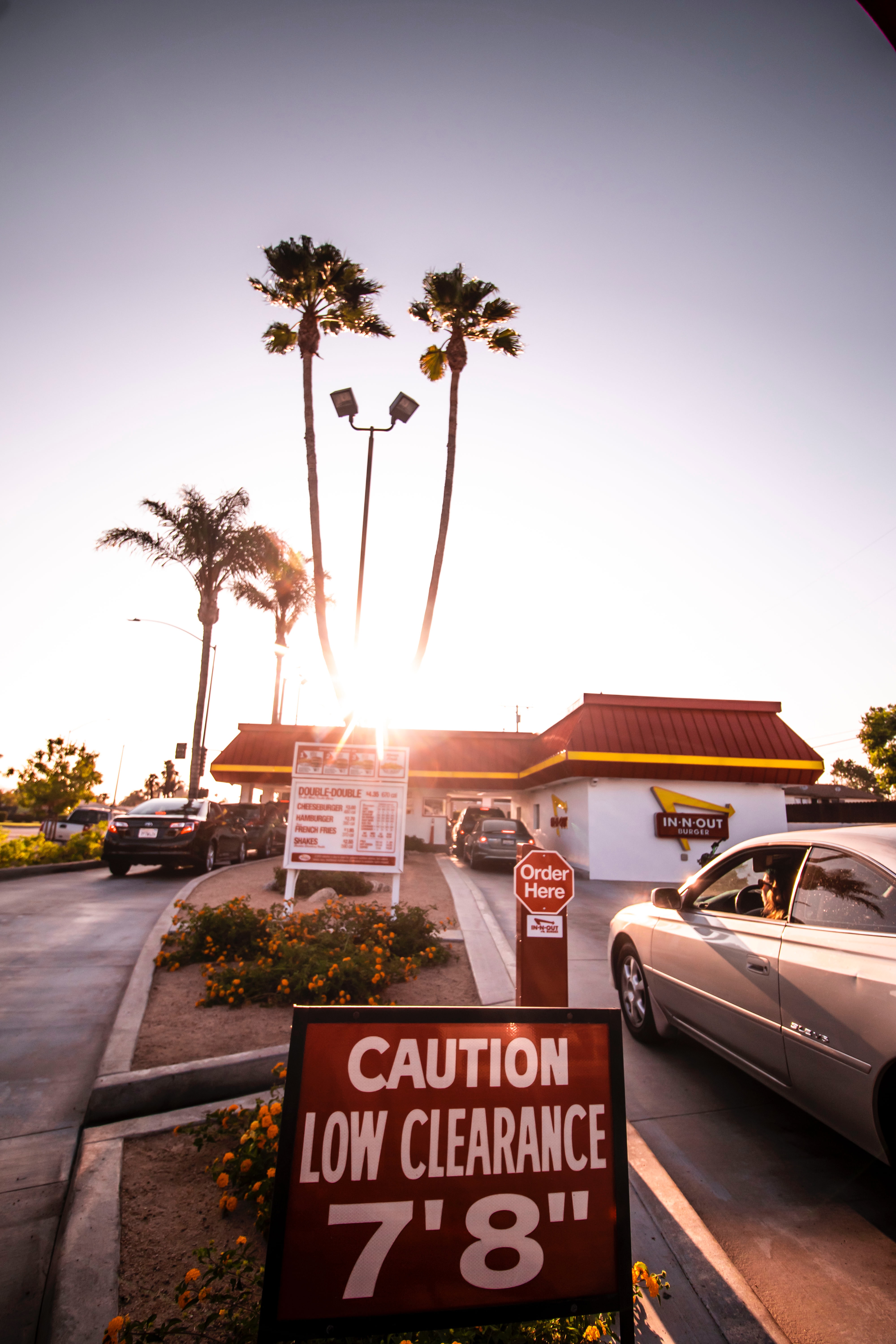 A fast food restaurant drive through lane, with palm trees in the background