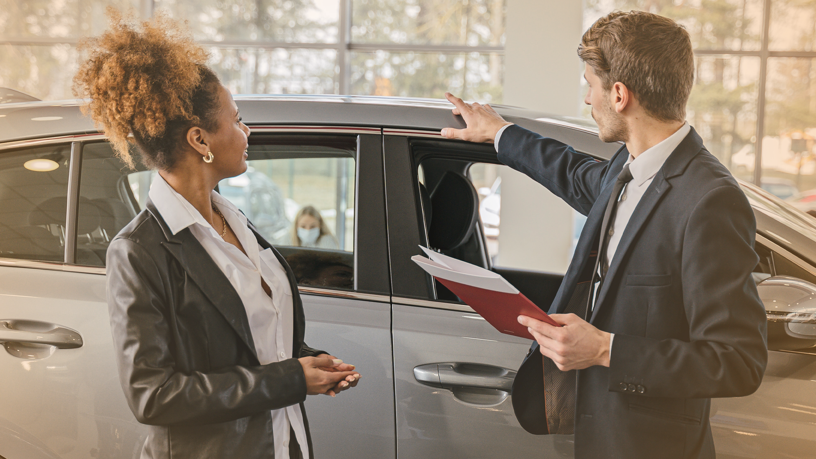 Woman looking at a car with dealership employee, relating to auto loan borrowers
