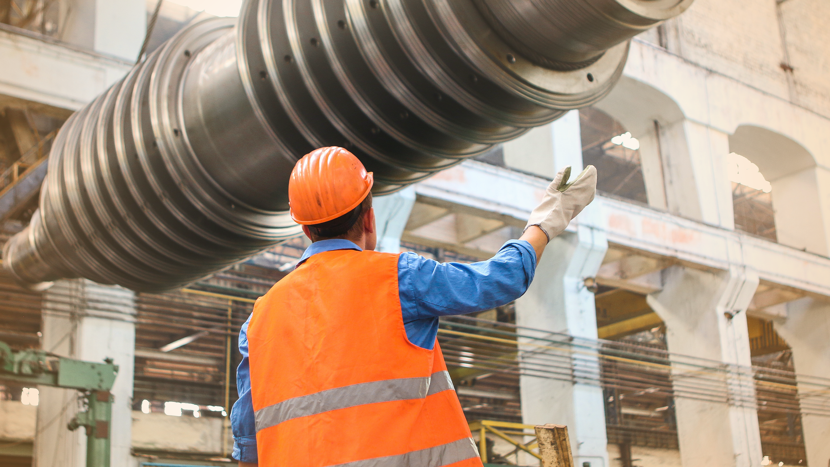 Factory worker in hard hat using technological equipment