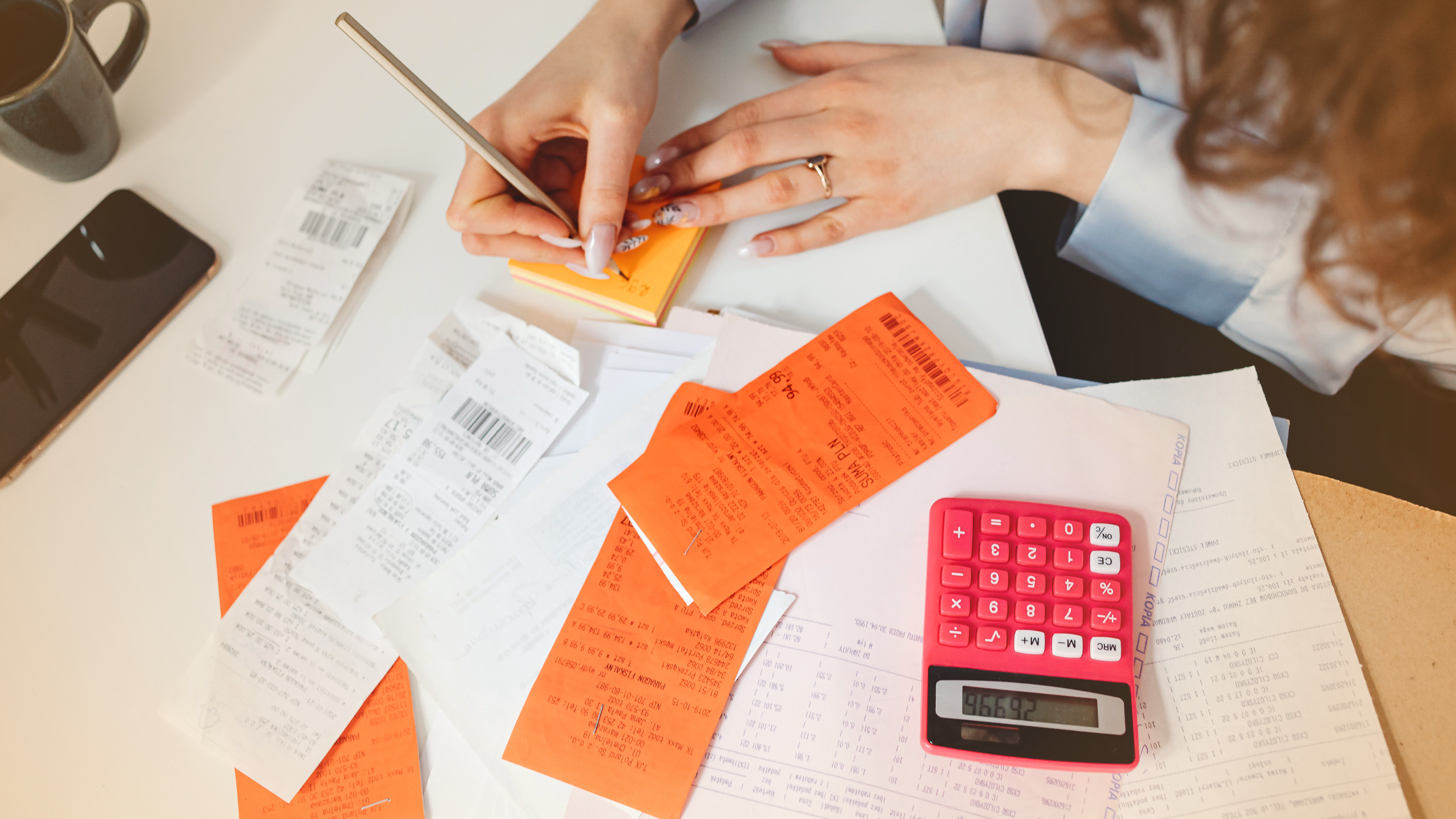 Woman calculating household expenses at a table with a calculator