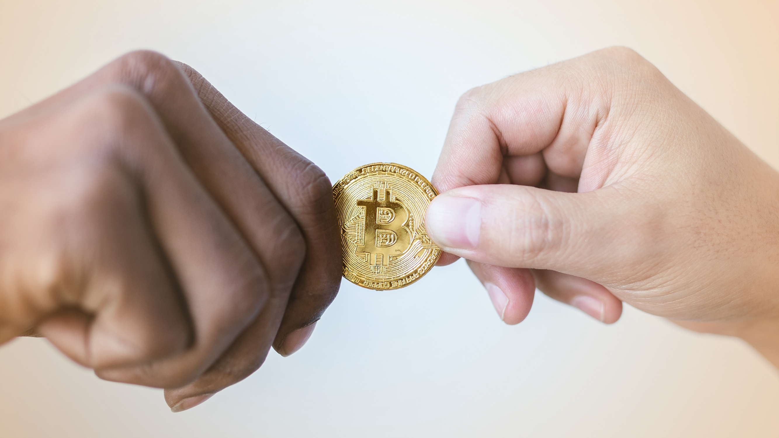 Two hands exchanging a Bitcoin cryptocurrency