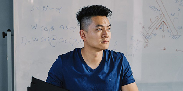 Jack Yao sits at his desk in front of a whiteboard with equations on it