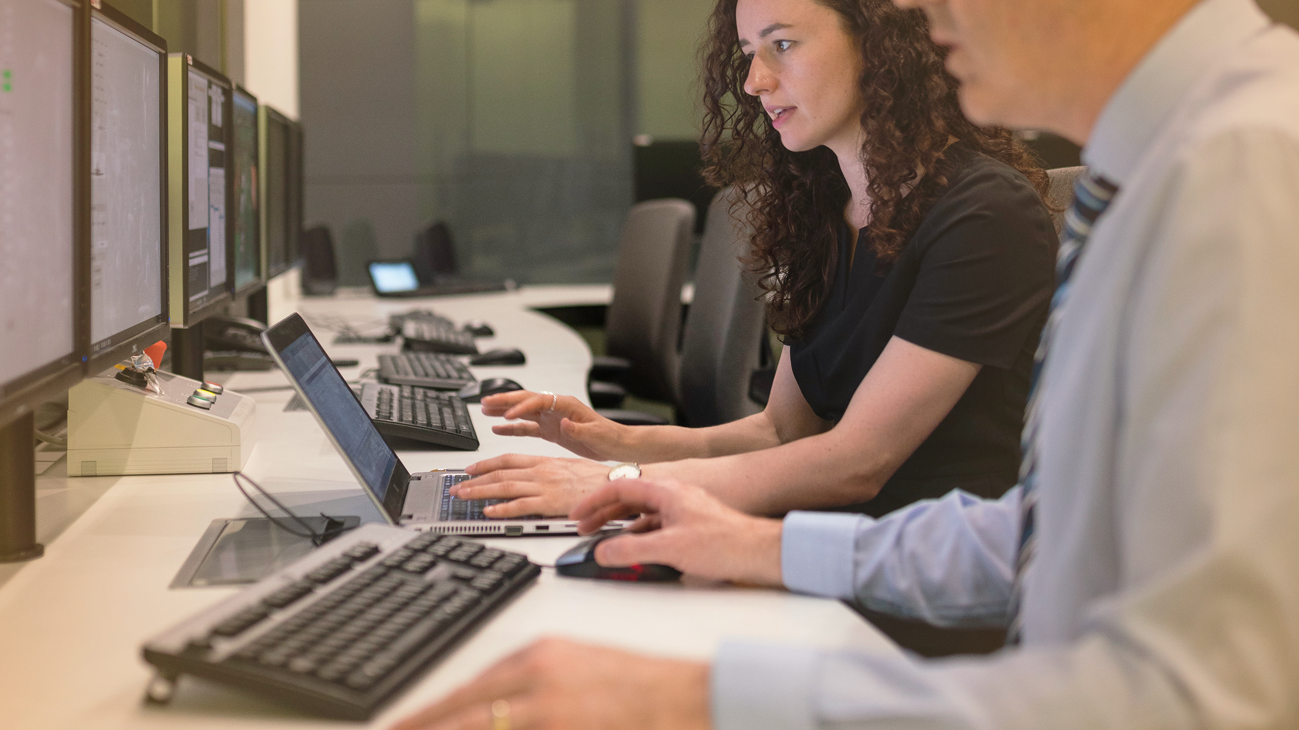Two people working on computers at a desk, relating to worker technology exposure