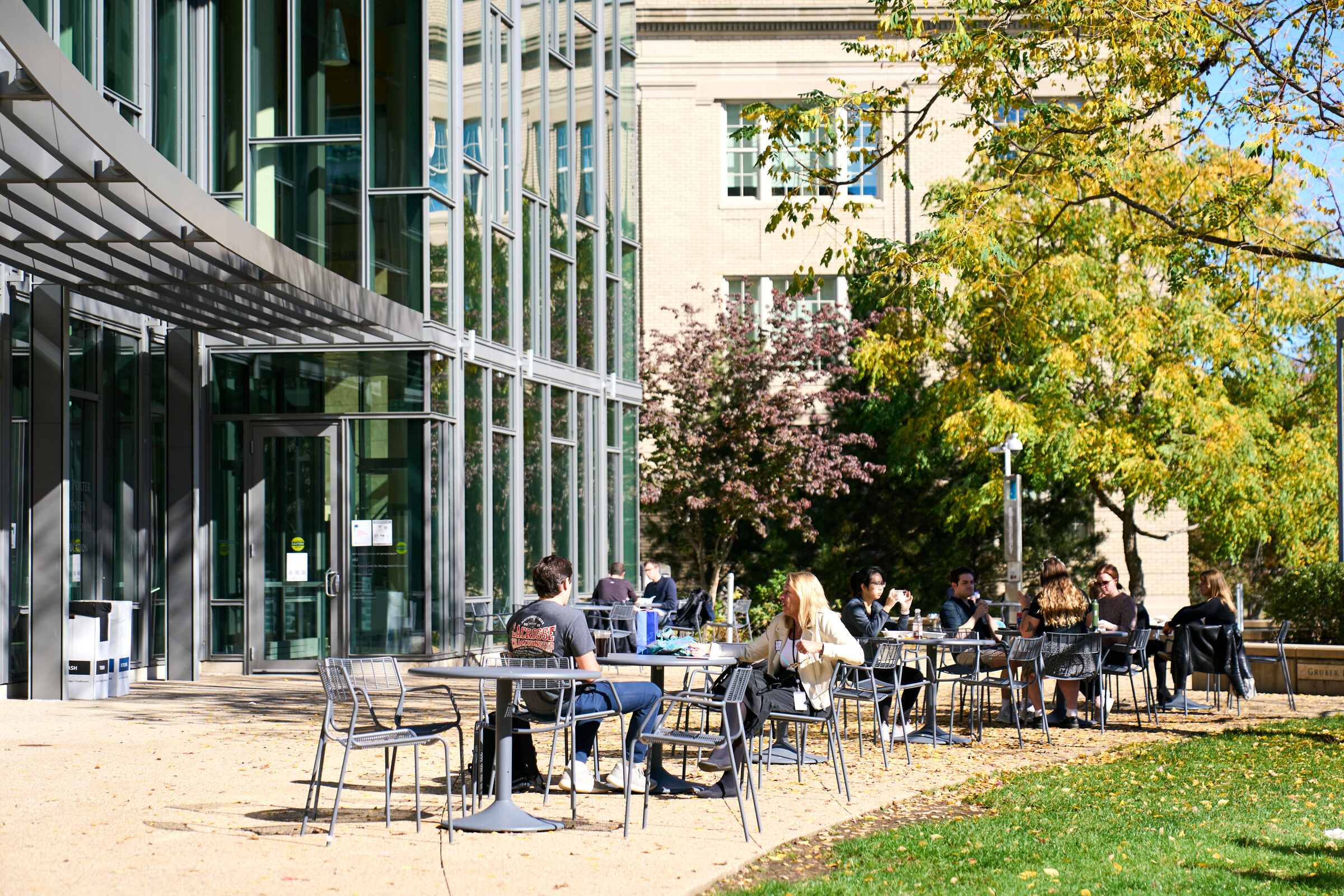 Students sit outside of E62 on a sunny day