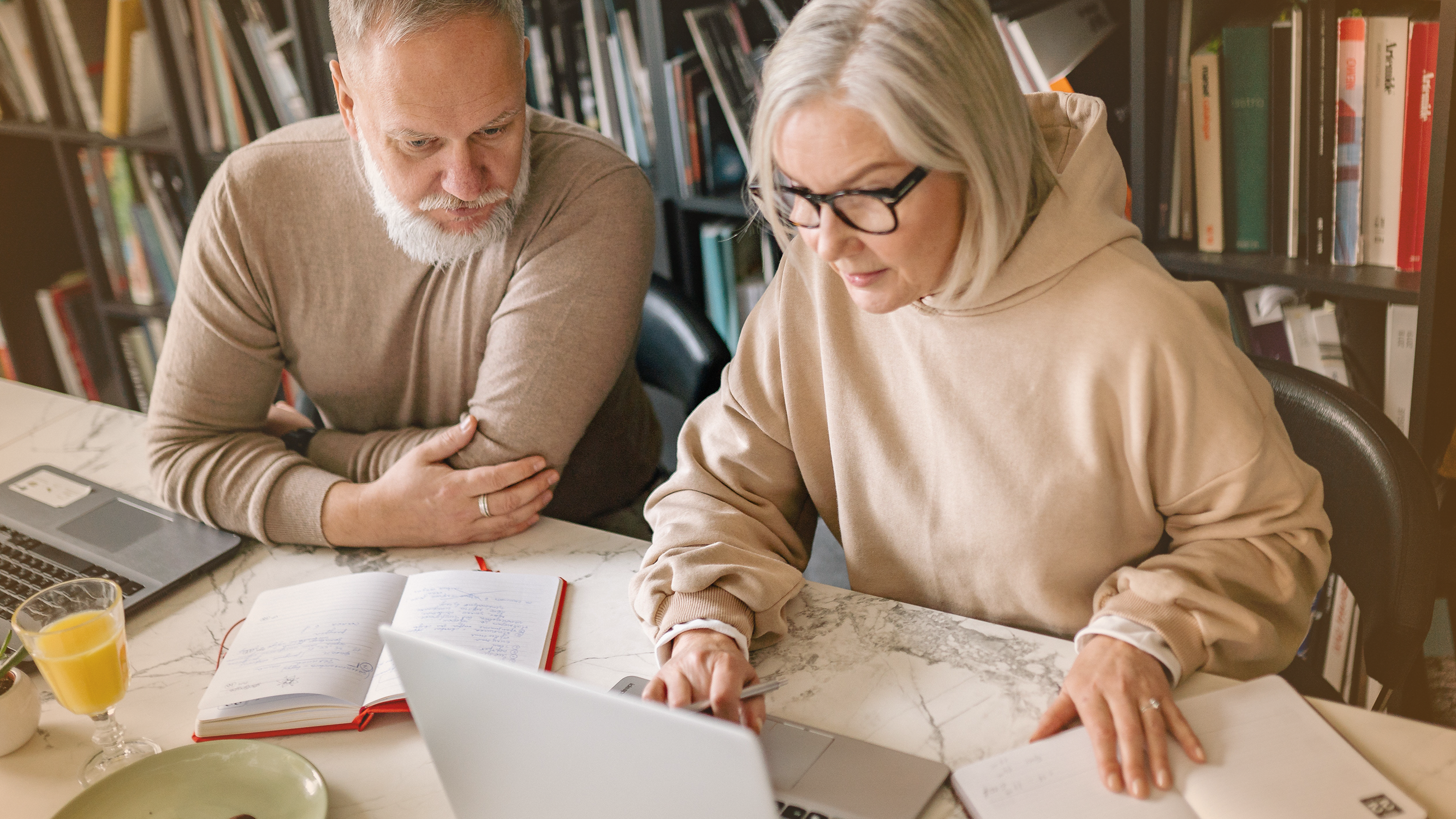 Couple looking at computer at a desk working on retirement savings and their investment portfolio