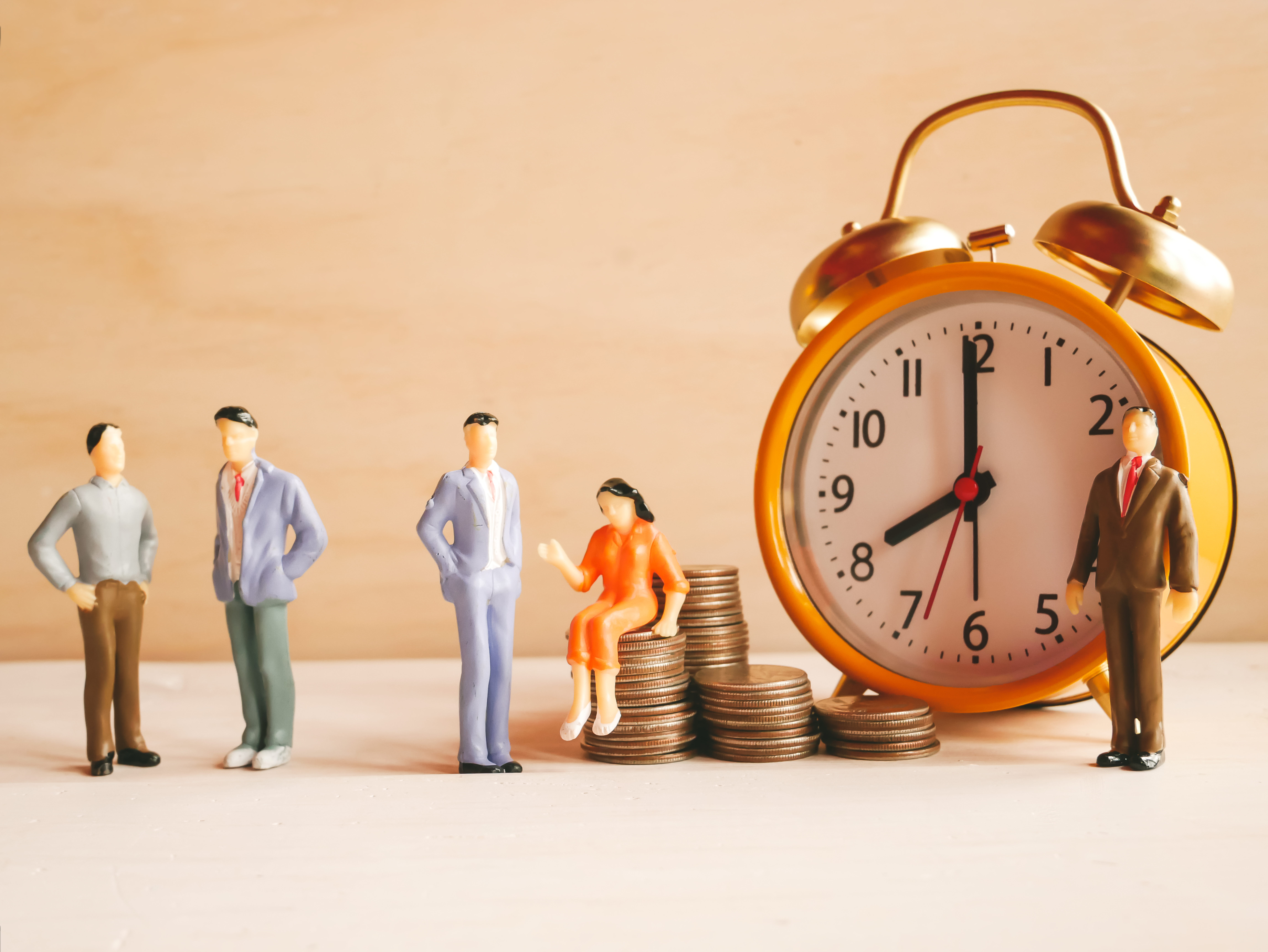 Analog clock with piles of coins and figures of adults.