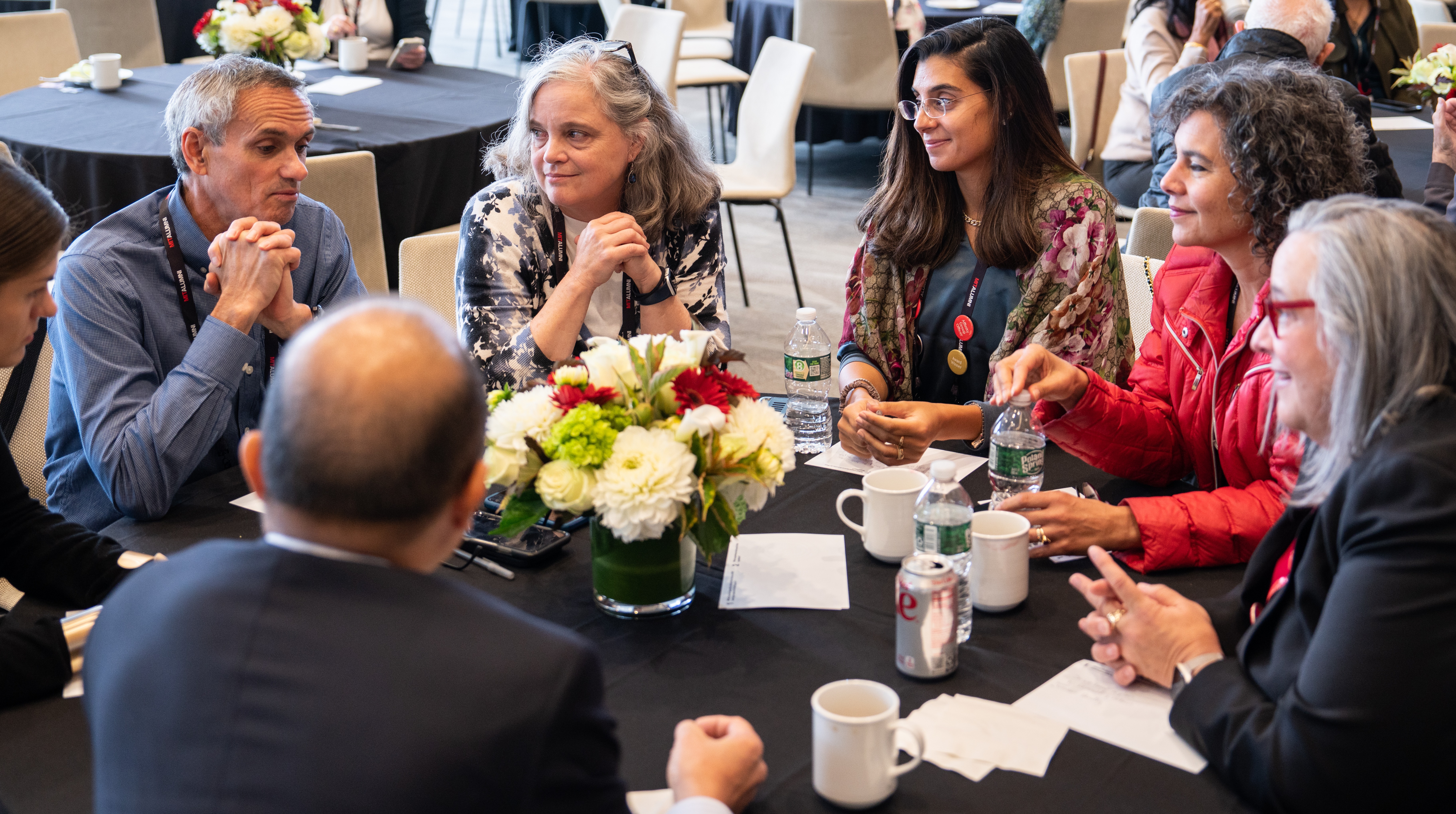 Several men and women gather around a table at a previous MIT Alumni Leadership Conference