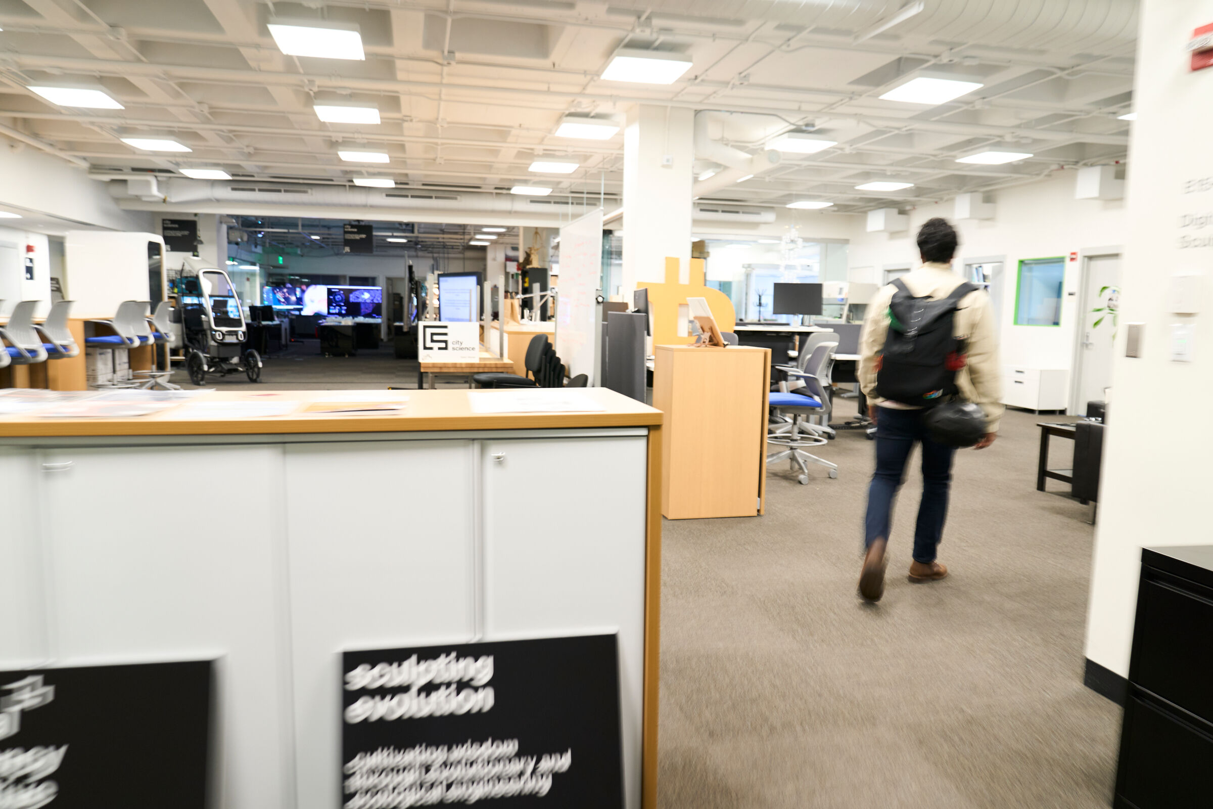 A student walks into an empty workspace on the MIT campus
