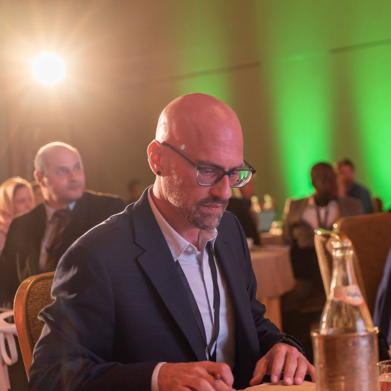 Photo of man in suit looking over papers on a table 