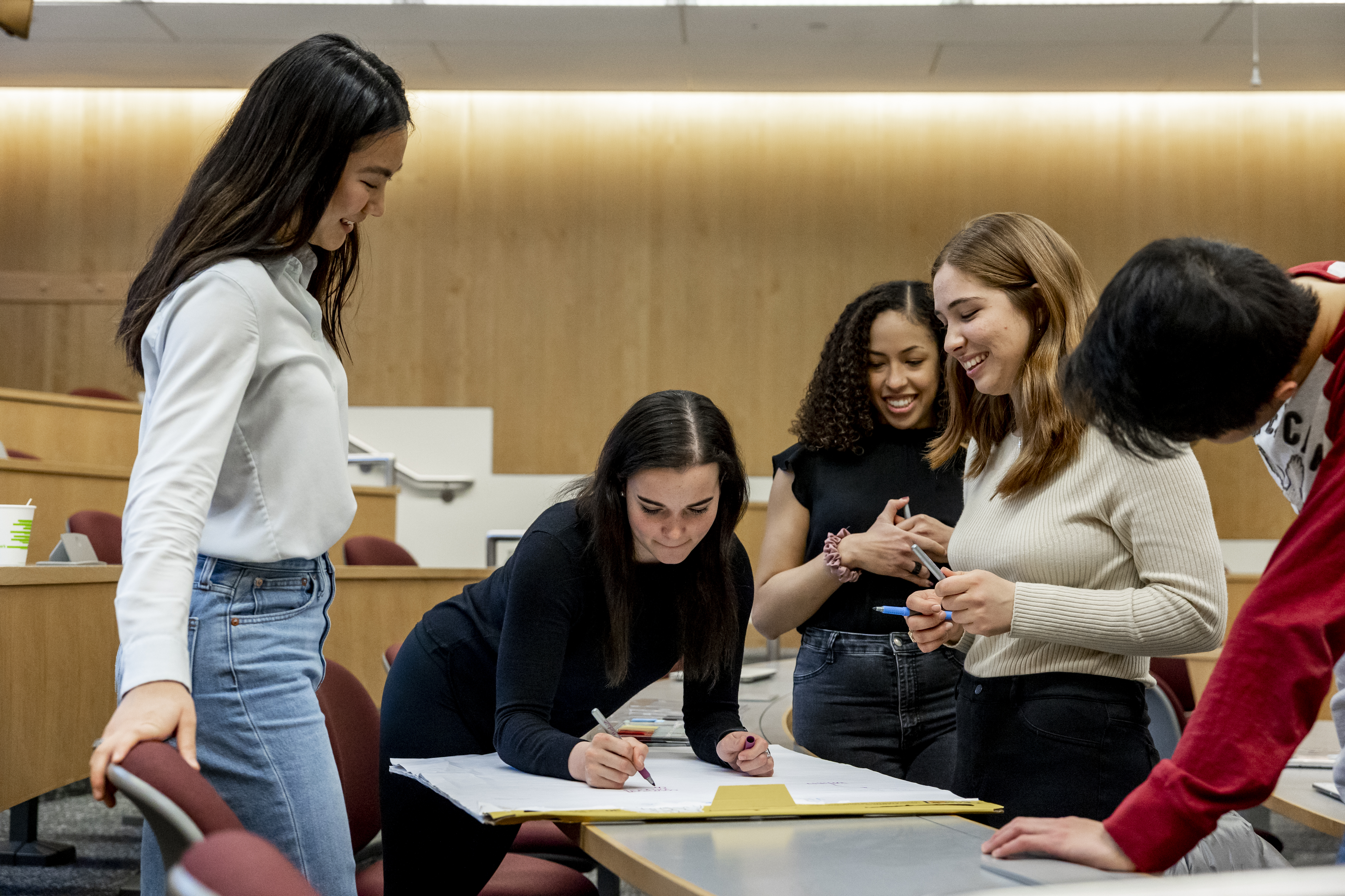 Five MIT Sloan students work on a project together.