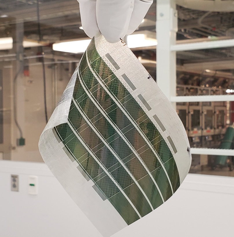 Image shows a gloved hand holding a flexible solar panel