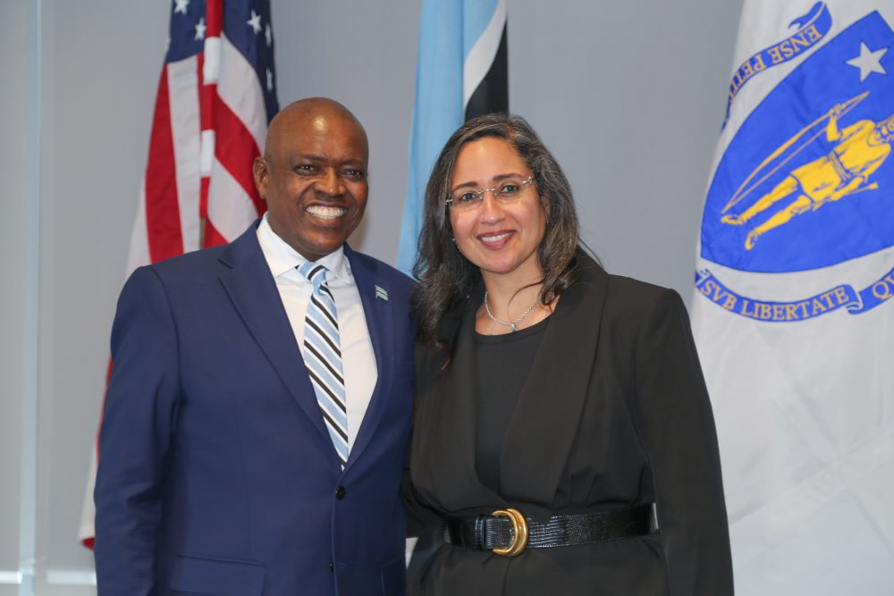 photo of a man and woman pictured toghether infront of the United States and Botswanaian Flags