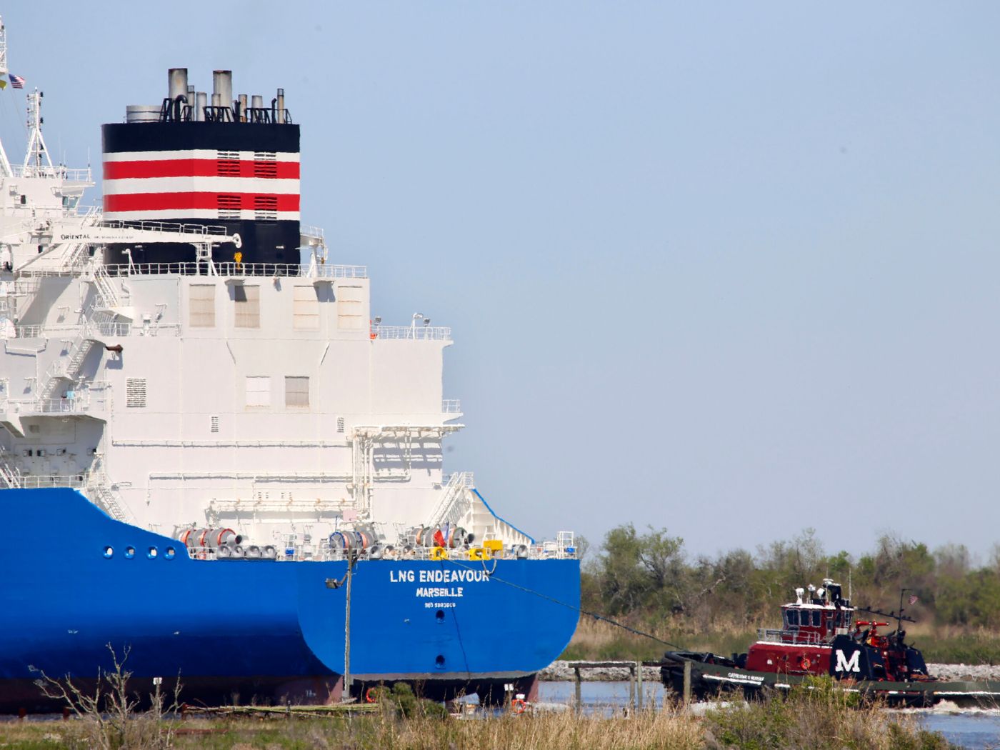 A tugboat helps guide a French ship, known as the LNG Endeavor, through Calcasieu Lake near Hackberry, La., on March 31, 2022.